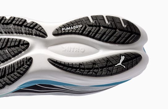 Close-up of a running shoe sole with black tread, white midsole, and Puma logo.