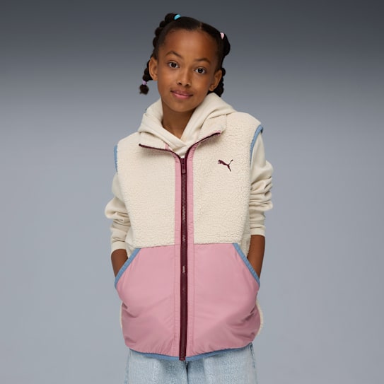 Against grey, a girl poses in a cream fleece gilet with pink detail over a hoodie.