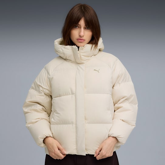 Against grey, a woman models a cream padded jacket with a subtle logo detail.