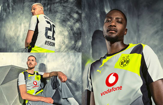 Three models showcase the Borussia Dortmund away kit against a grey abstract backdrop.