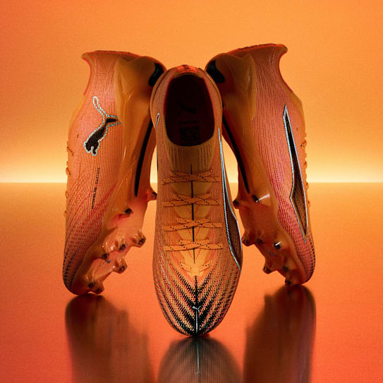 A blue football boot is displayed with a blurred racing car on a gradient backdrop.