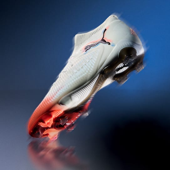 Gros plan d'une chaussure de football avec des détails rouges et noirs sur fond bleu.