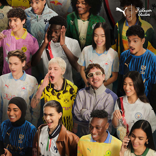 Enthusiastic diverse models wear colourful Kidsuper football jerseys, expressing excitement and joy.
