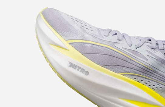 Close-up of a grey running shoe with a bright yellow sole featuring the word 'NITRO'.