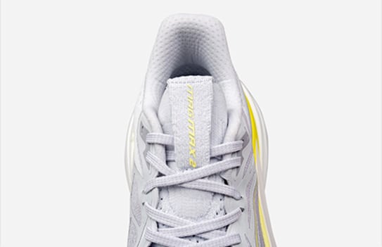 Close-up of a grey and yellow Puma running shoe with laced closure on a plain background.