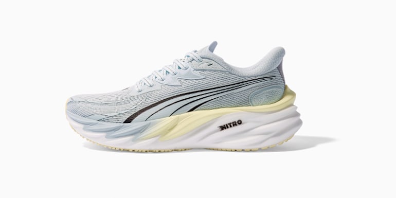 Vor einem weißen Hintergrund, ein hellblauer Laufschuh mit dem Wort NITRO auf der dicken weißen Sohle.