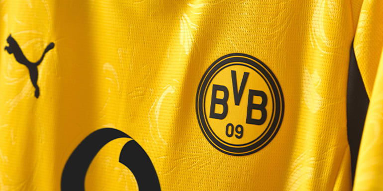 Close-up of a yellow BVB football shirt with the team logo and brand emblem.